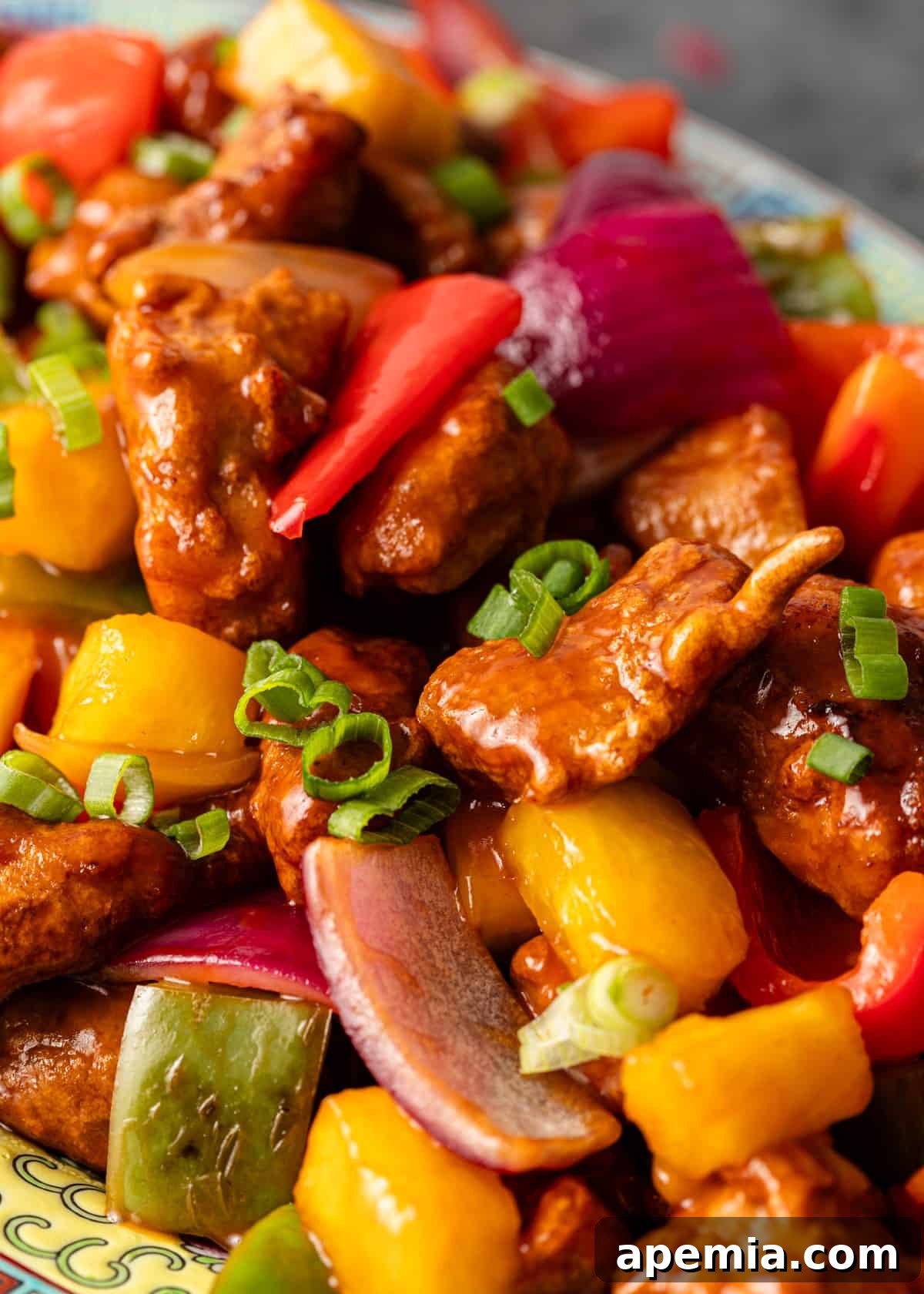 extreme closeup: a serving of sweet and sour pork with glossy sauce and visible vegetables