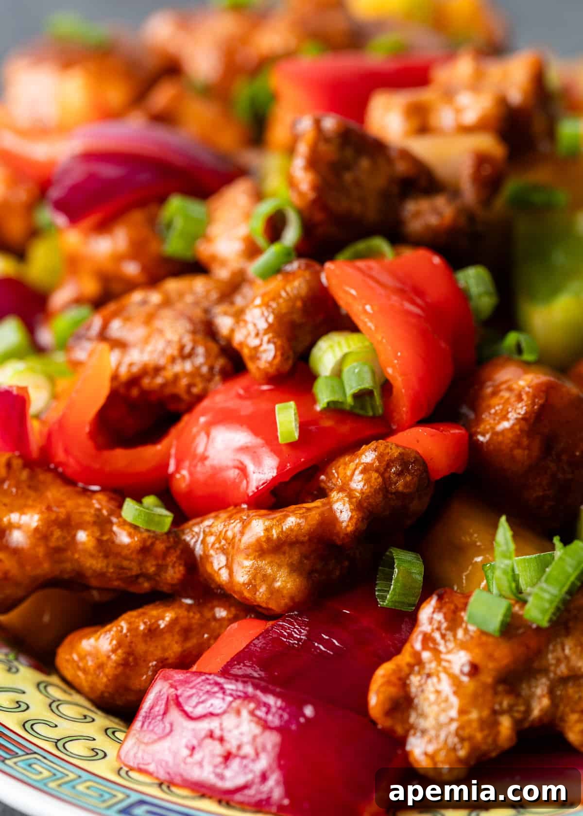 extreme closeup: perfectly glazed sweet and sour pork with colorful vegetables on a serving dish