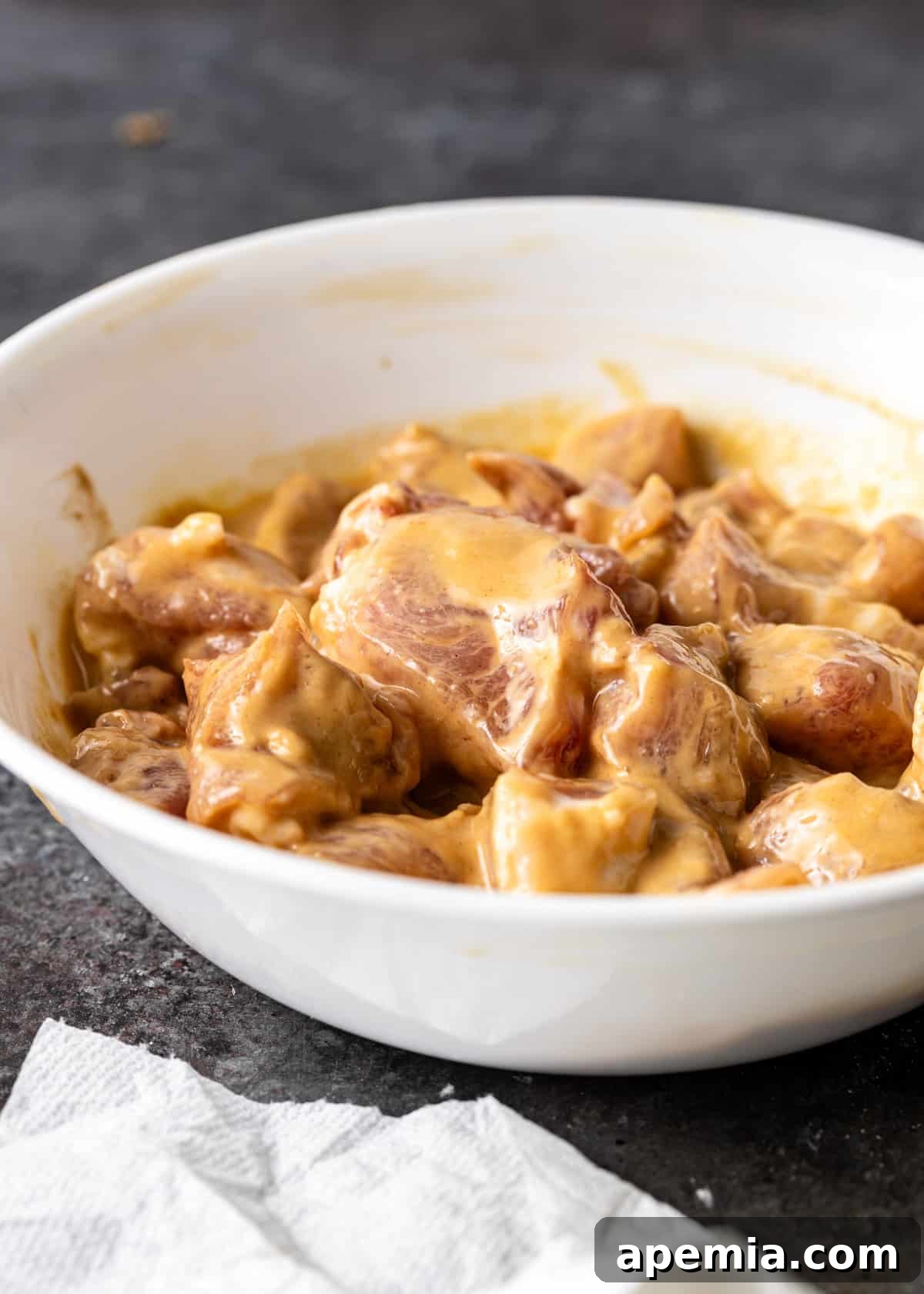 process shot: pork marinating in a savory velvet batter mixture in a bowl