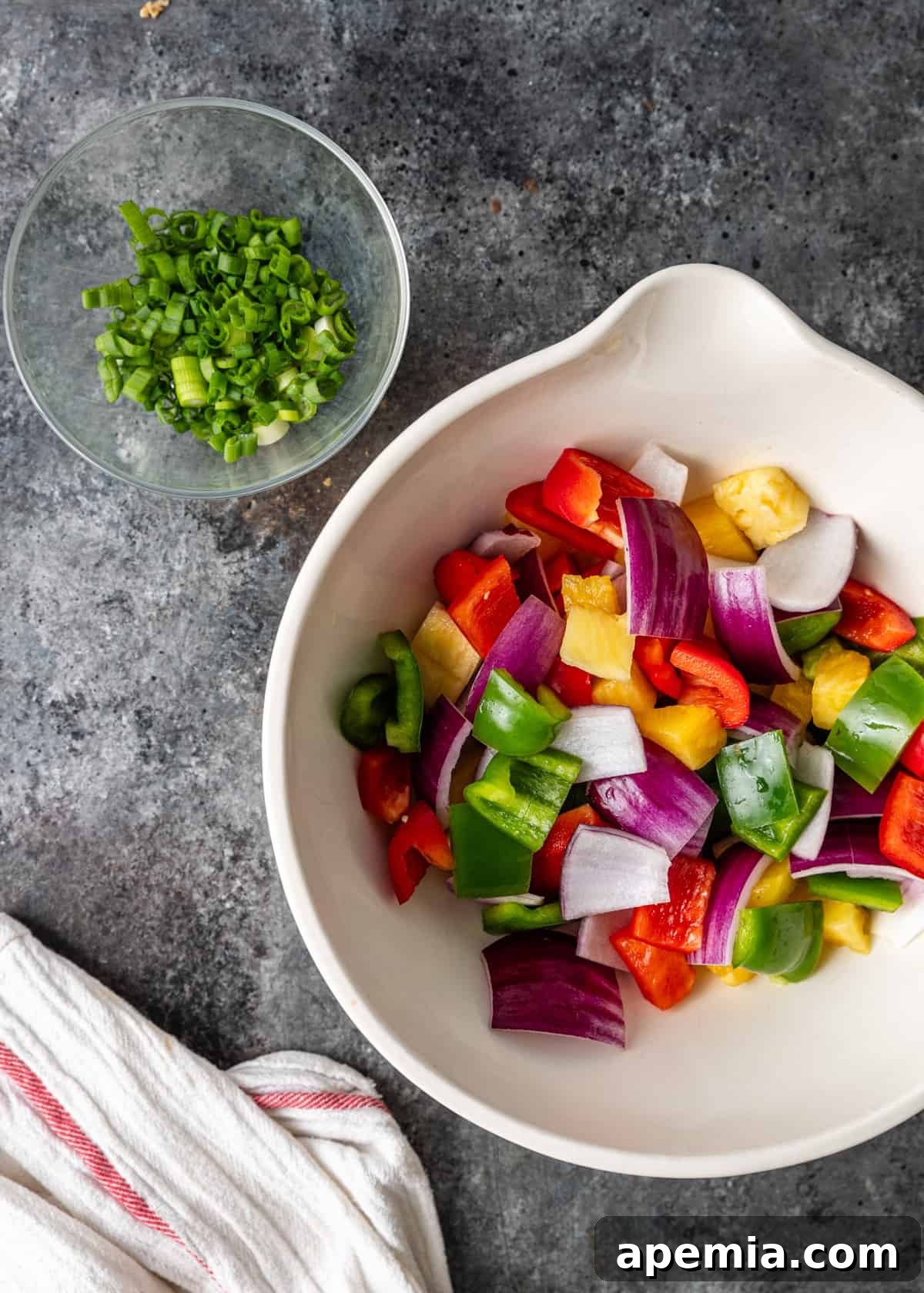 Overhead view of perfectly chopped vegetables, including bell peppers and onions, arranged for sweet and sour chicken preparation.