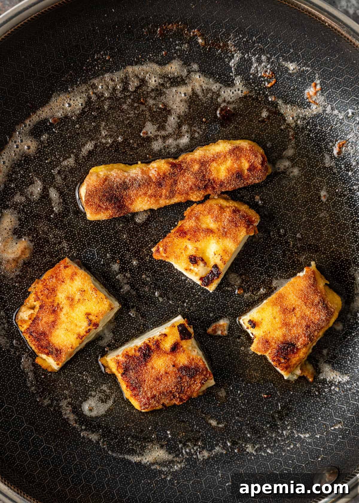 Fiery Greek Cheese Saganaki 6 Process shot of my Saganaki recipe being pan-seared in a skillet, showing the cheese developing a golden crust.