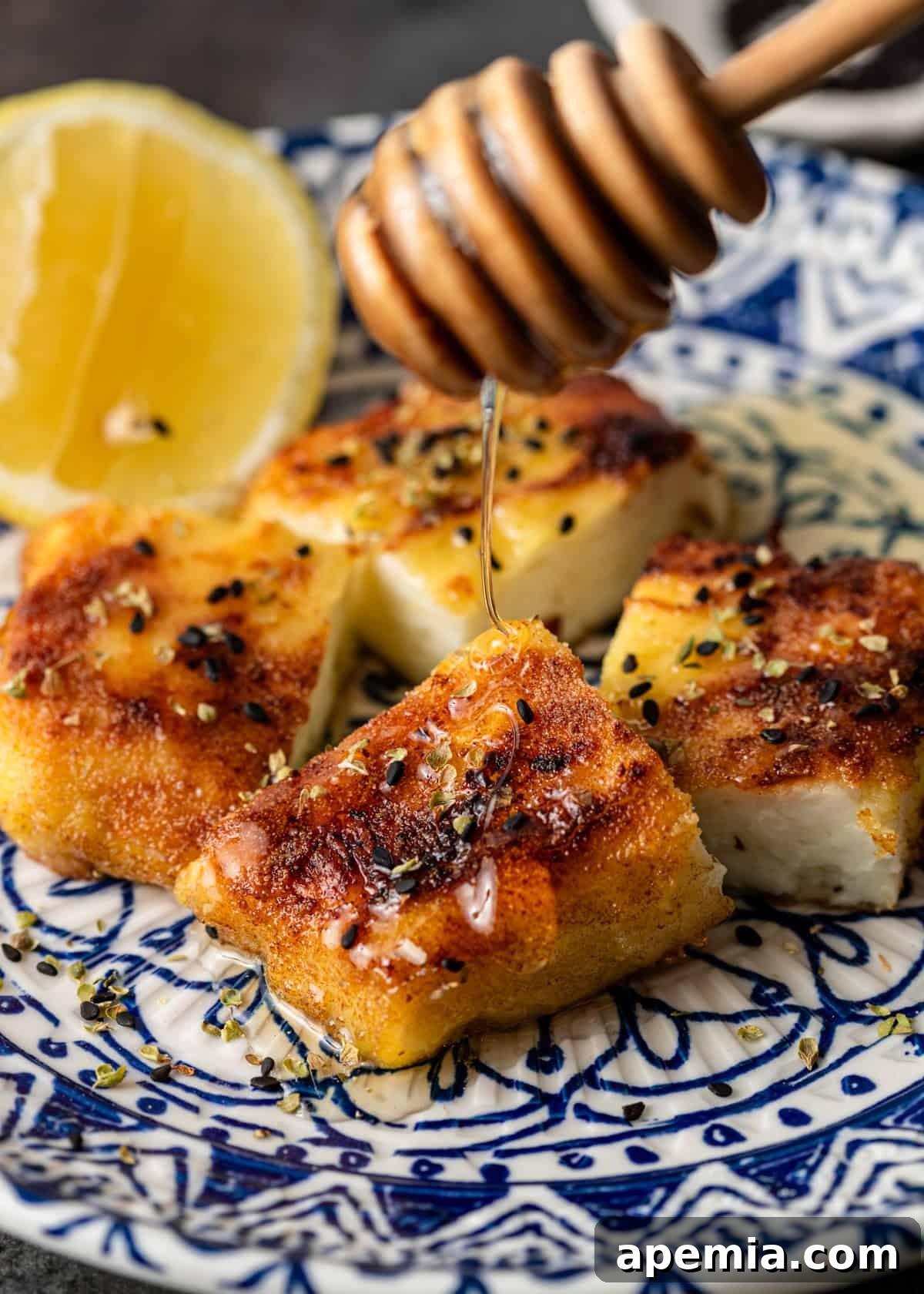 Fiery Greek Cheese Saganaki 8 Close-up shot of a honey dipper drizzling golden honey over freshly prepared Saganaki, highlighting the enticing glaze.