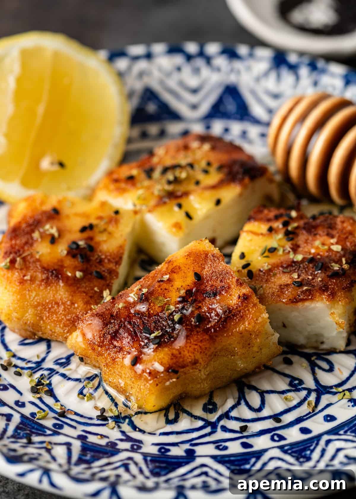 Fiery Greek Cheese Saganaki 9 Close-up overhead view of four pieces of my Saganaki recipe, beautifully garnished with fresh herbs and a drizzle of honey.