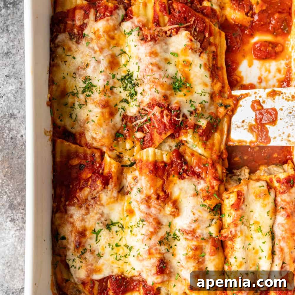 overhead shot: a golden brown baking dish filled with saucy manicotti, with a slice already served