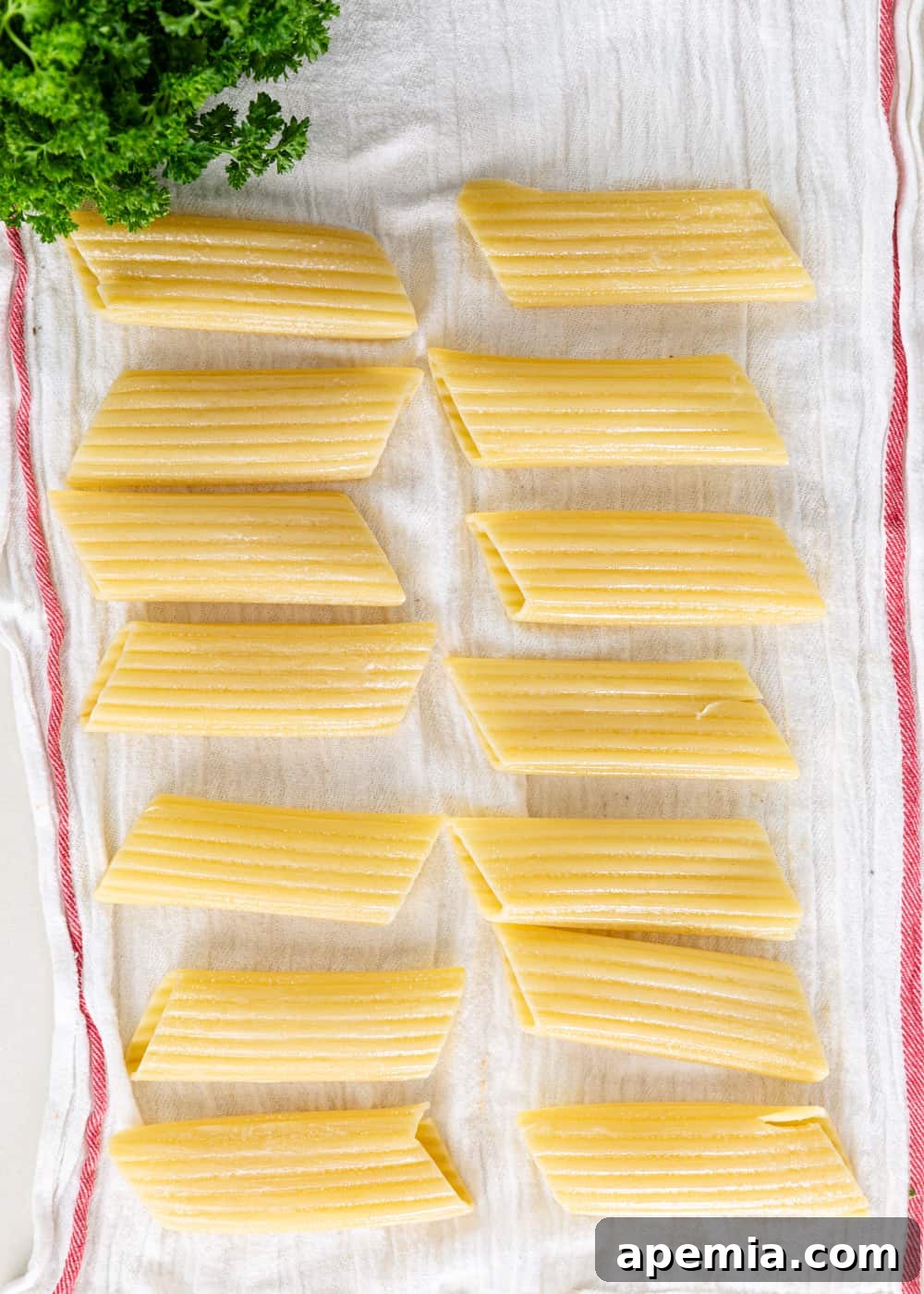 overhead process shot: freshly cooked manicotti noodles draining on a clean towel