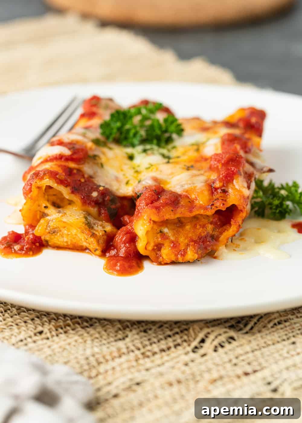 a serving of our beef and cheese manicotti on a plate, generously covered with sauce and melted cheese