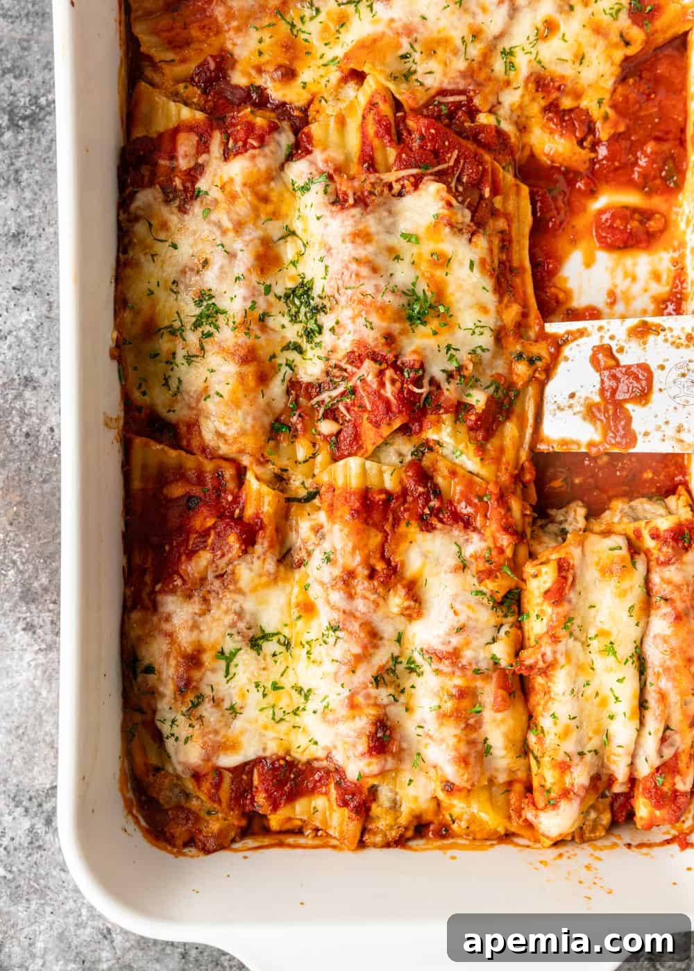 overhead shot: a baking dish full of freshly baked manicotti, with a rich sauce and melted, golden-brown cheese topping