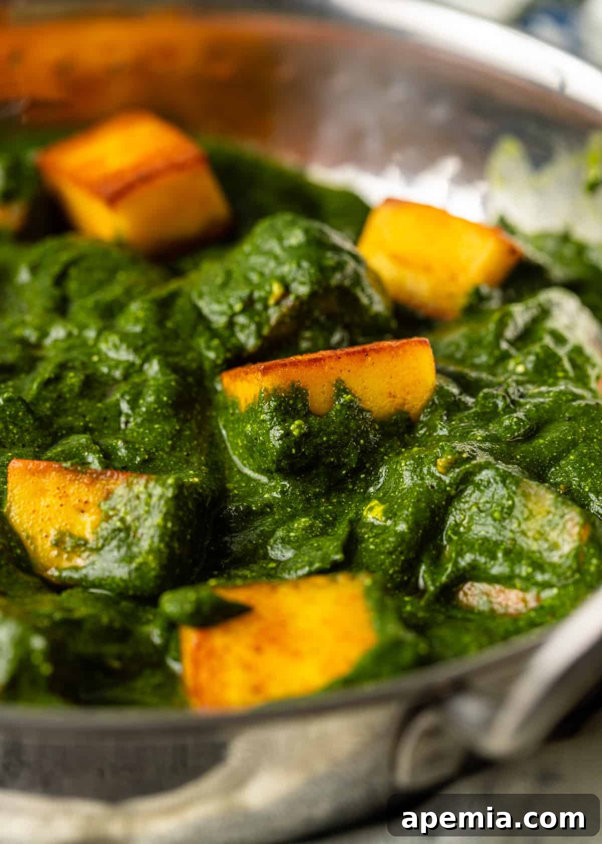 Palak Paneer Creamy Spinach and Indian Cheese Curry 3 A captivating close-up of Palak Paneer, highlighting the lush green spinach gravy and perfectly cooked, slightly crispy paneer cheese cubes, showcasing its irresistible texture.
