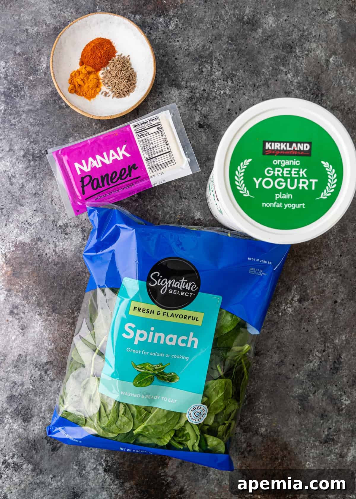 Palak Paneer Creamy Spinach and Indian Cheese Curry 4 An organized overhead shot showcasing an array of fresh ingredients, including vibrant spinach, blocks of paneer, various whole and ground spices, and garlic, prepared for a delicious saag paneer recipe.
