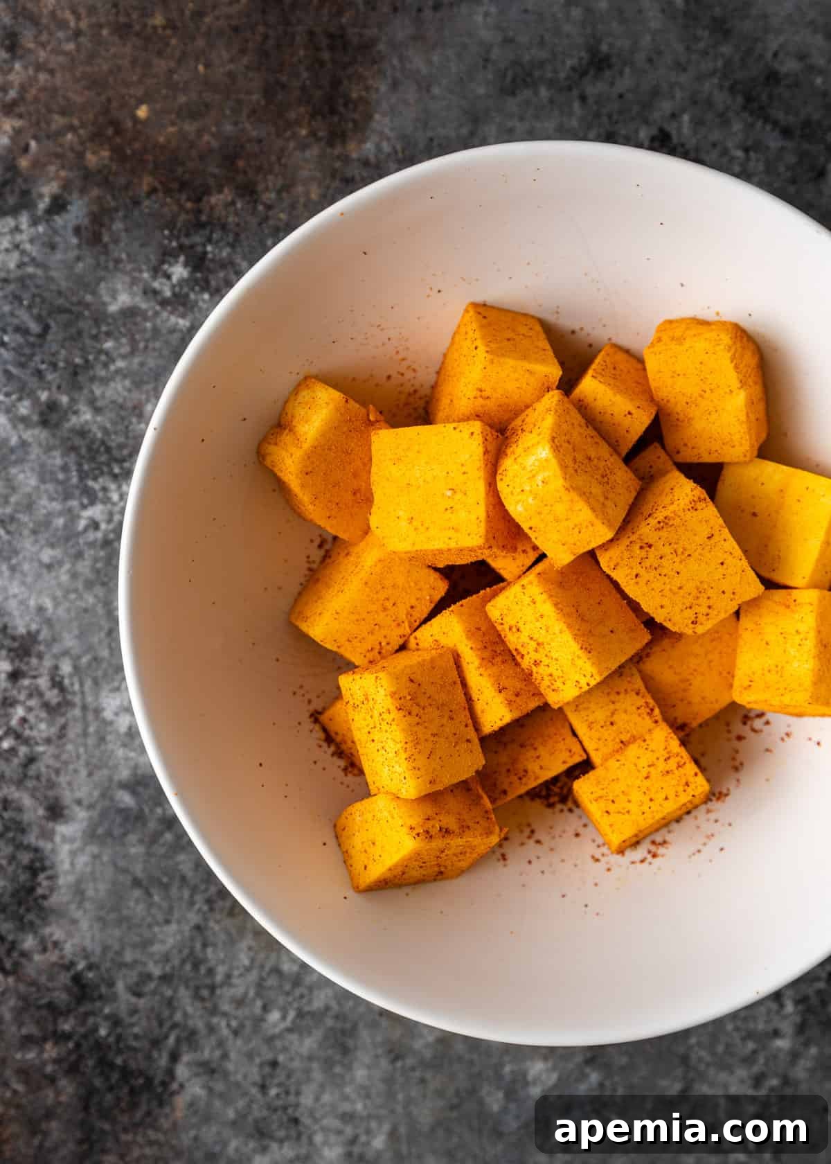 Palak Paneer Creamy Spinach and Indian Cheese Curry 5 An overhead shot depicting paneer cheese cubes being thoroughly tossed in a bowl with a vibrant mix of turmeric and chili powder, ensuring each piece is evenly coated.