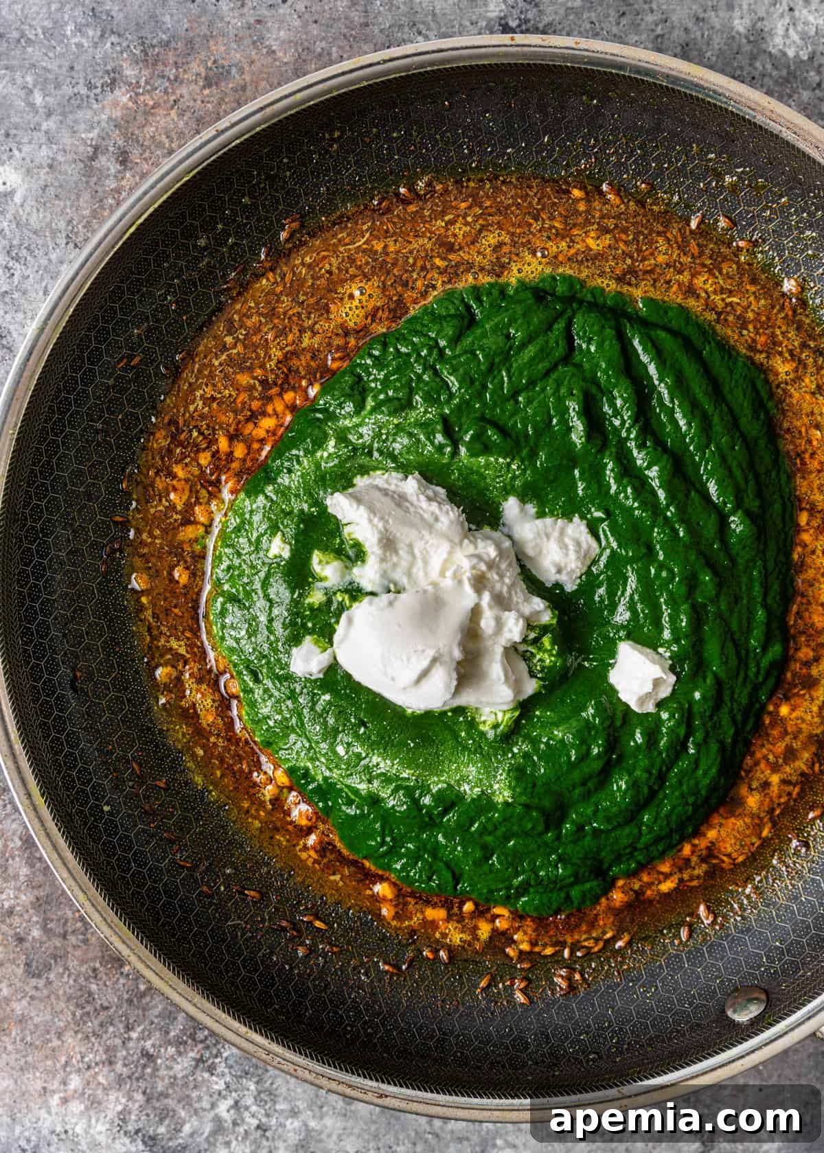 Palak Paneer Creamy Spinach and Indian Cheese Curry 8 An overhead process shot of aromatic tempered spices, combined with the spinach purée and creamy yogurt, simmering gently in a skillet to form the rich and harmonious palak paneer gravy.