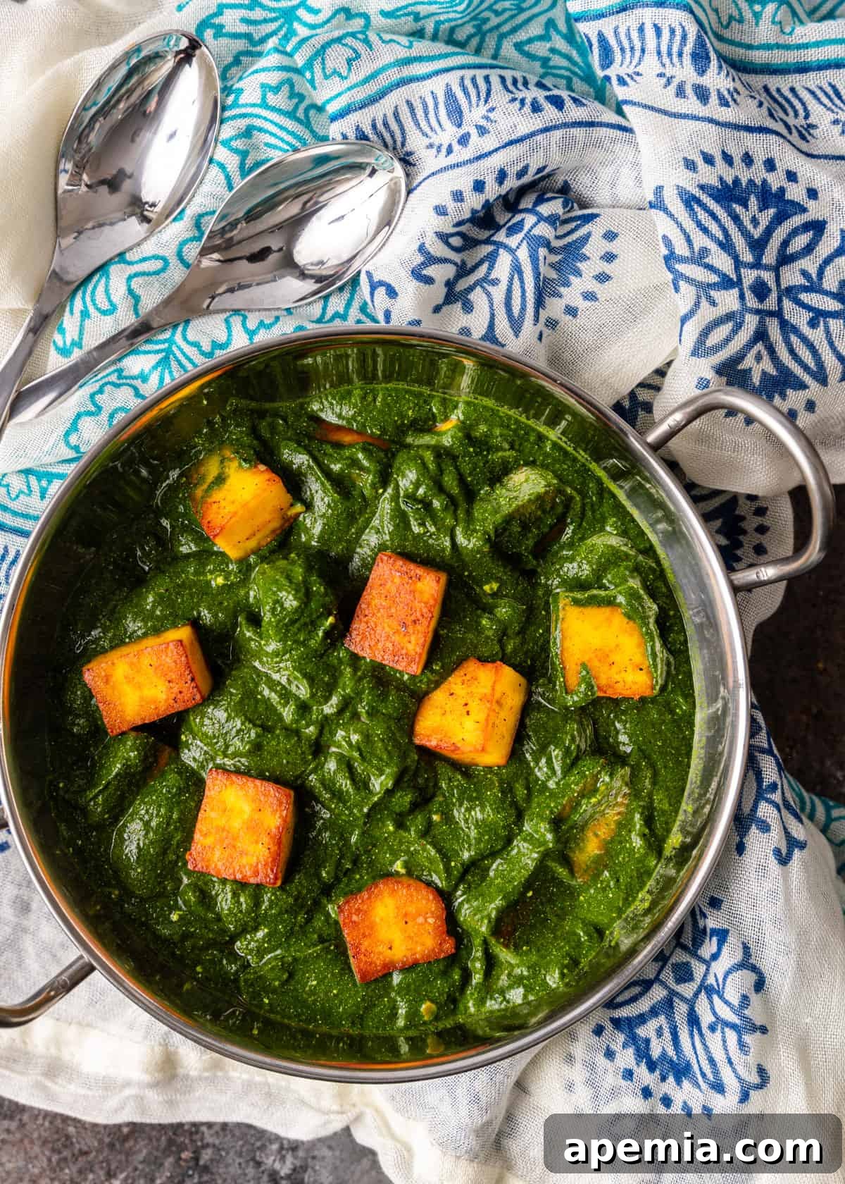 Palak Paneer Creamy Spinach and Indian Cheese Curry 10 An overhead view of Palak Paneer served in a traditional metal dish, garnished with fresh cilantro leaves, showcasing its rich green color and the perfectly cooked paneer cubes.