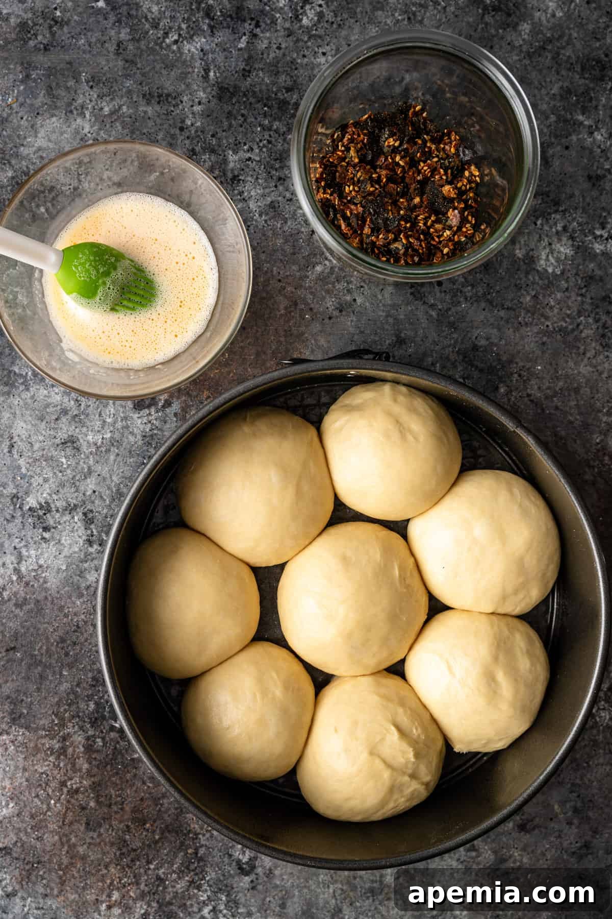 Overhead process shot: Dough balls arranged in a pan, rising for 30 minutes before baking.
