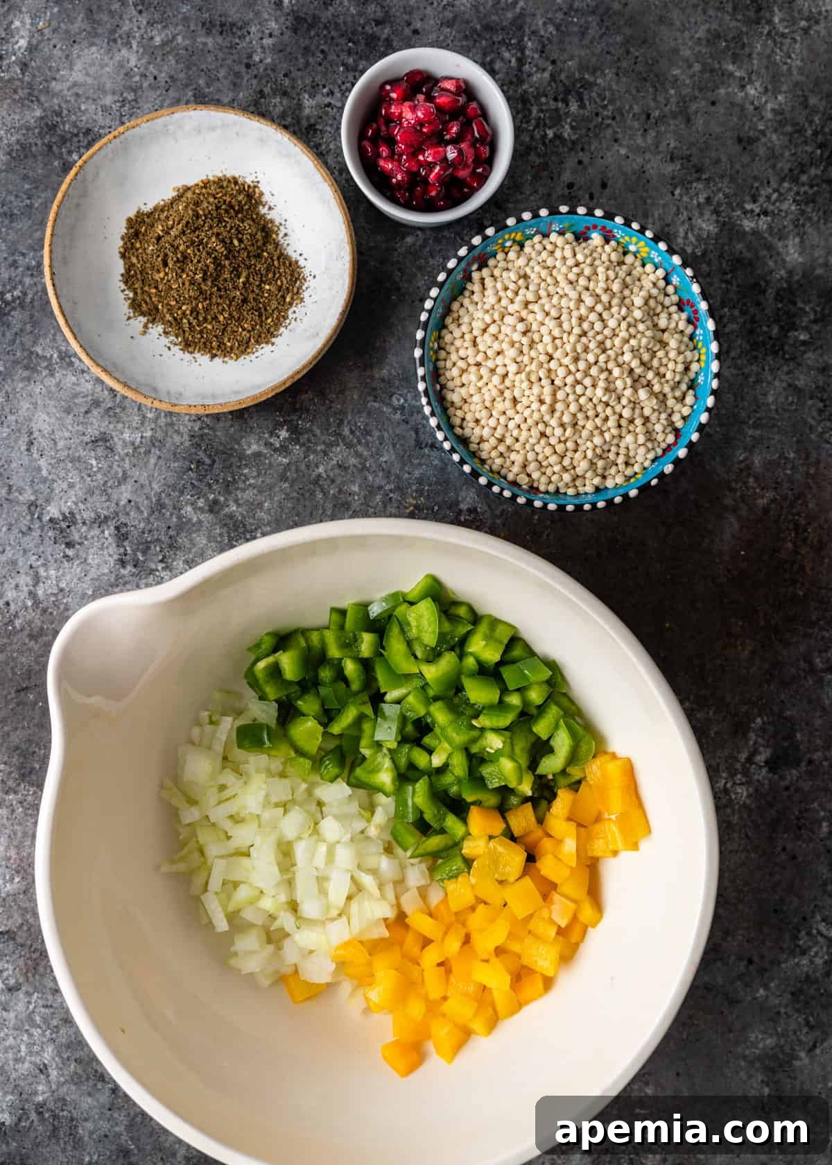 Aromatic Za'atar Couscous and Vibrant Market Vegetables 4 A vibrant flat lay showcasing all the fresh ingredients required for Za'atar Pearl Couscous: bell peppers, onion, pearl couscous, pomegranate, parsley, za'atar, and olive oil.