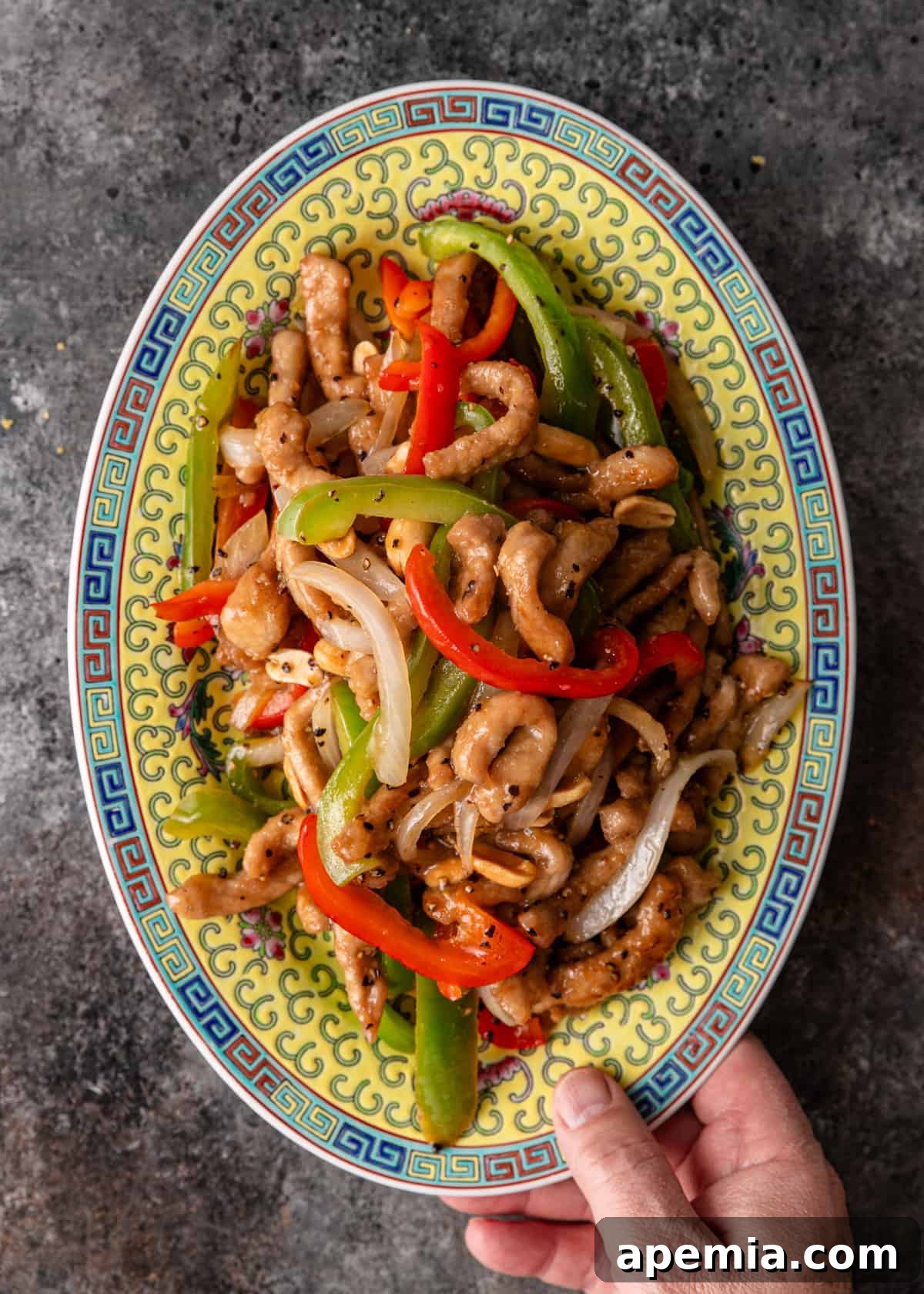 overhead: a hand holding a large platter of my black pepper and vinegar pork stir fry recipe