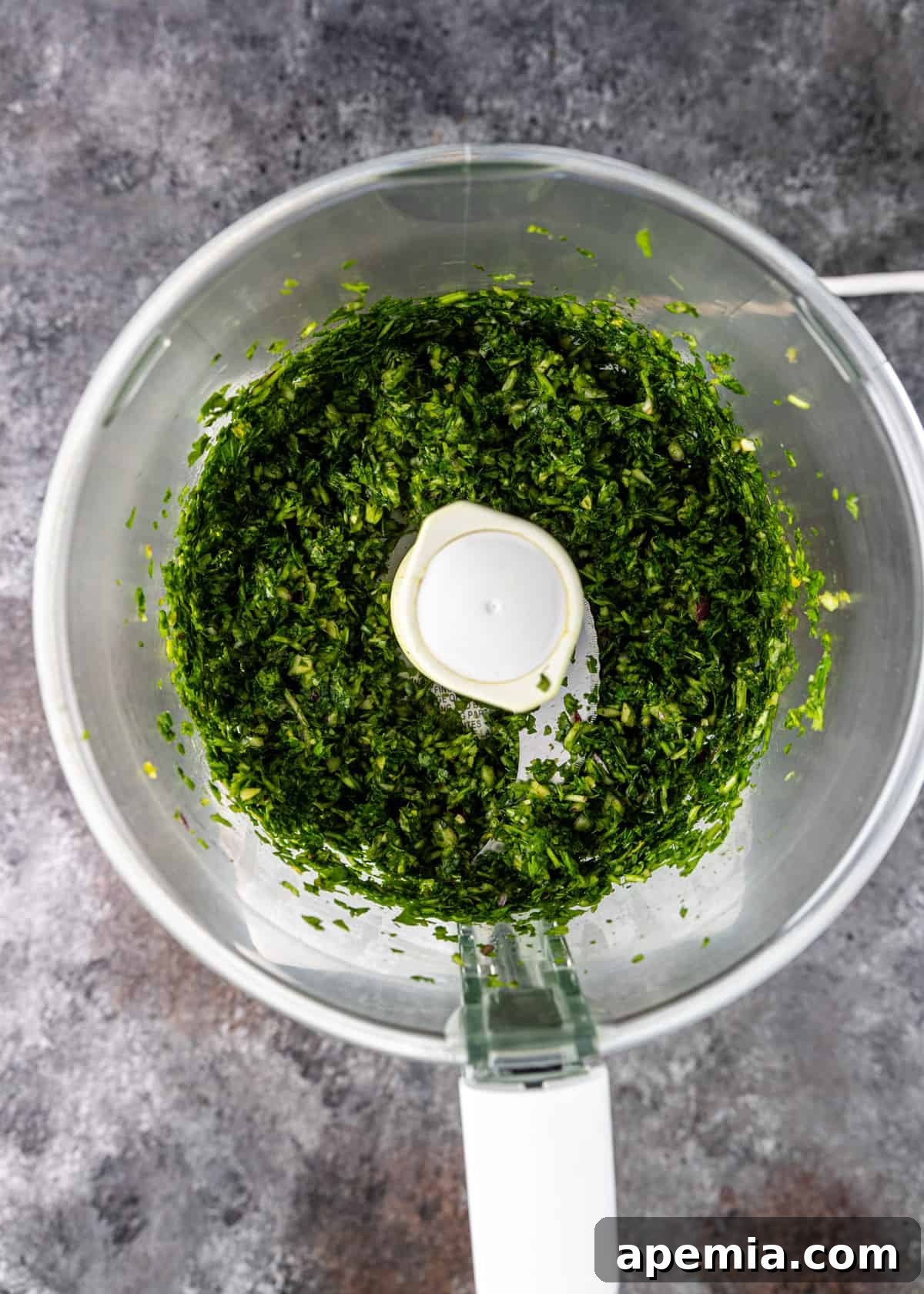 overhead process shot: herbs, onion, and garlic blended in food processor