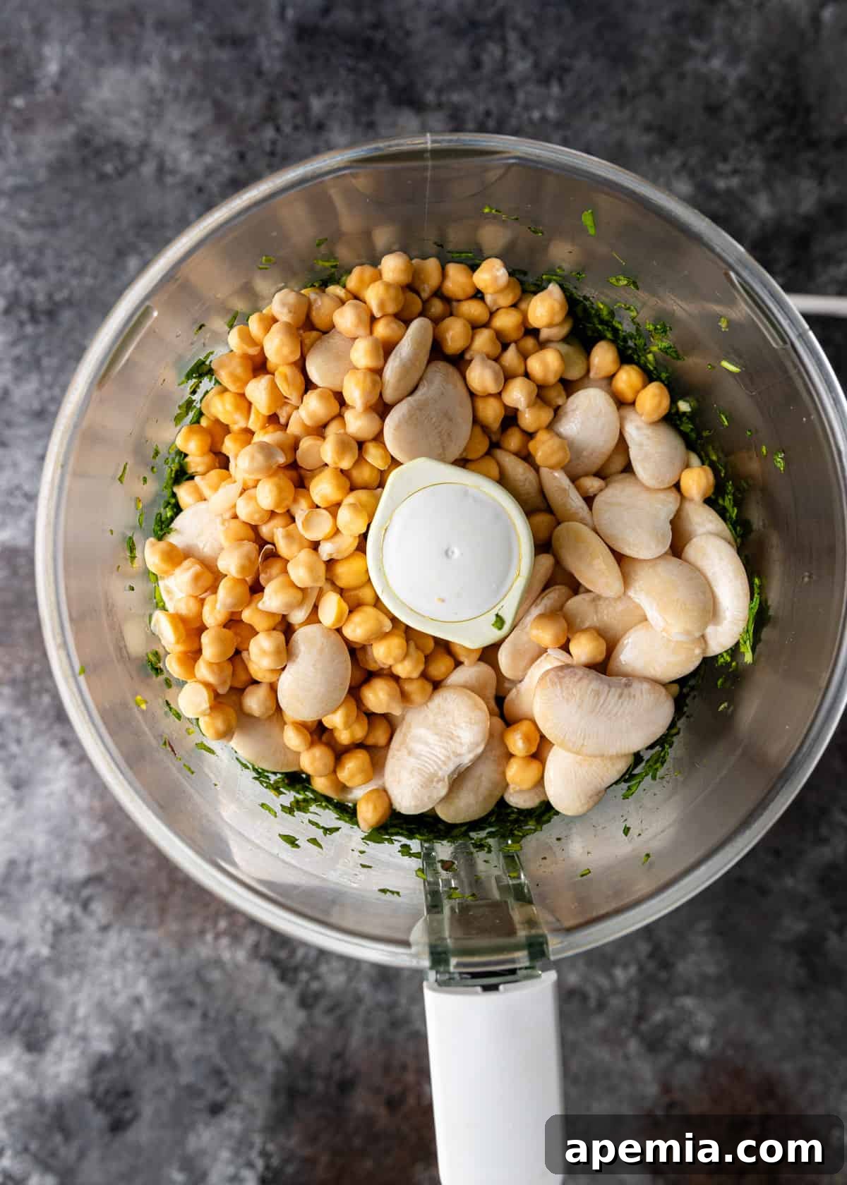 overhead process shot: adding beans to the herbs in food processor