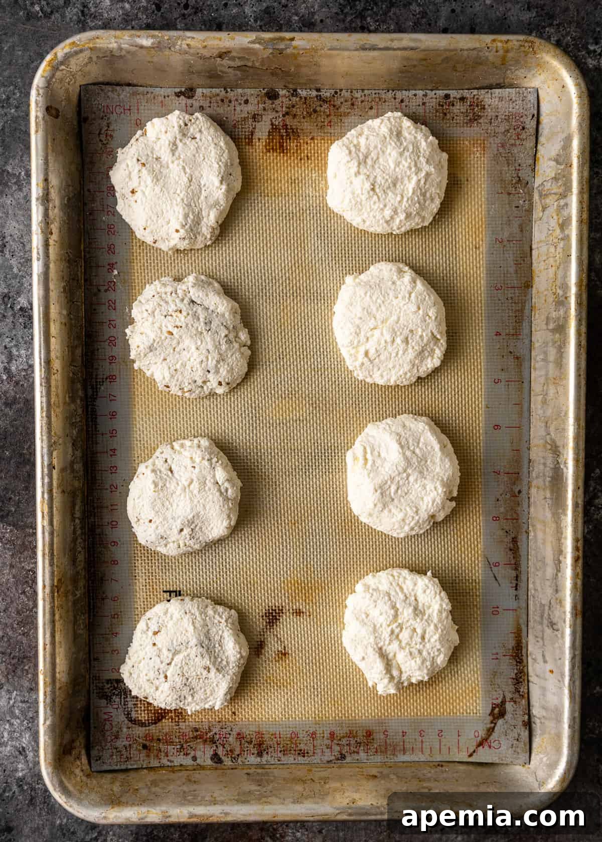 Overhead view of formed Jibin cheese patties on a baking sheet, ready for refrigeration.