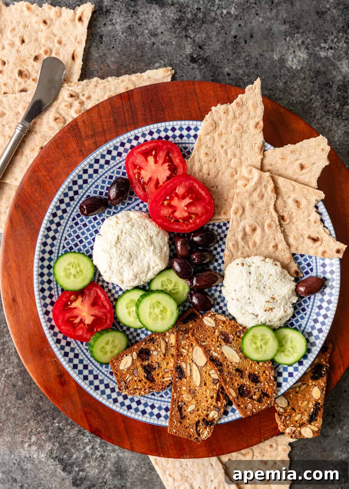 Overhead shot of a vibrant platter featuring Lebanese white cheese, an assortment of crackers, fresh tomato slices, crisp cucumber slices, and black olives.