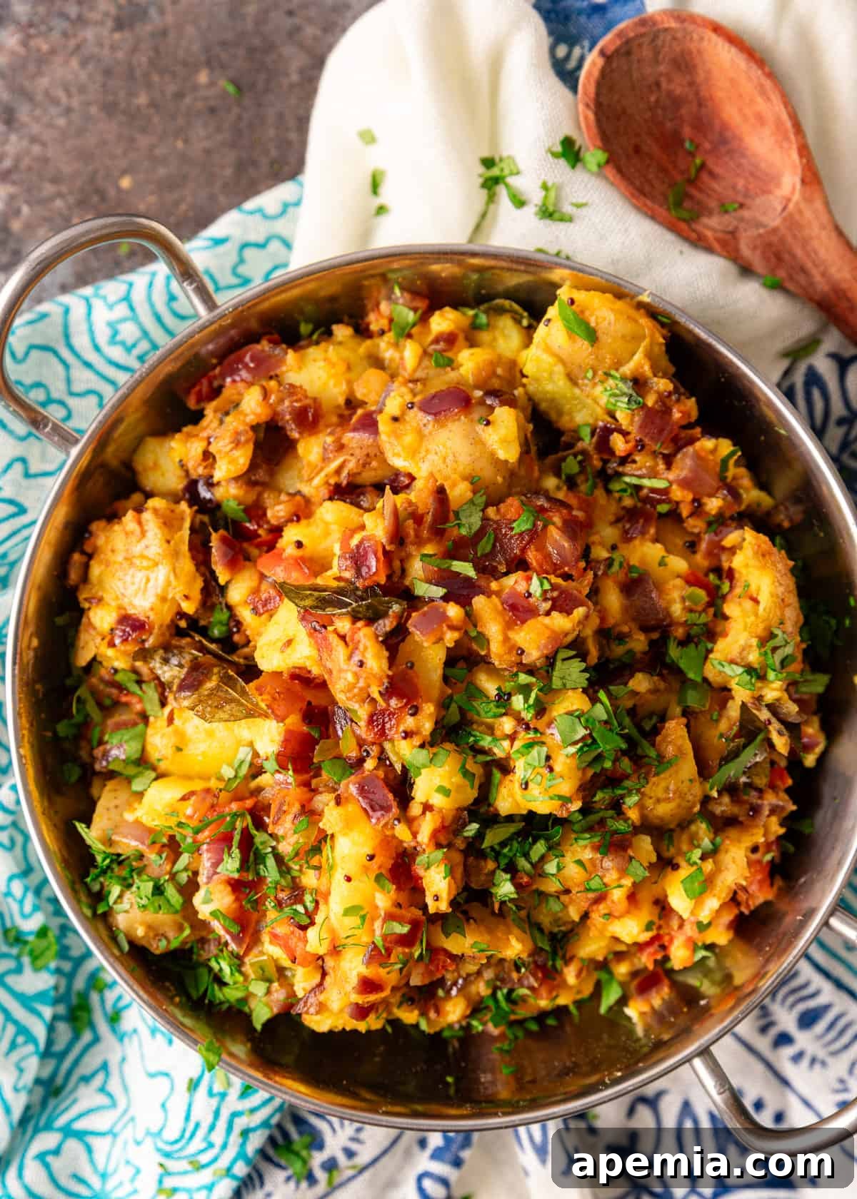overhead: a large bowl of my potato curry recipe with fresh herbs on top, served with rice
