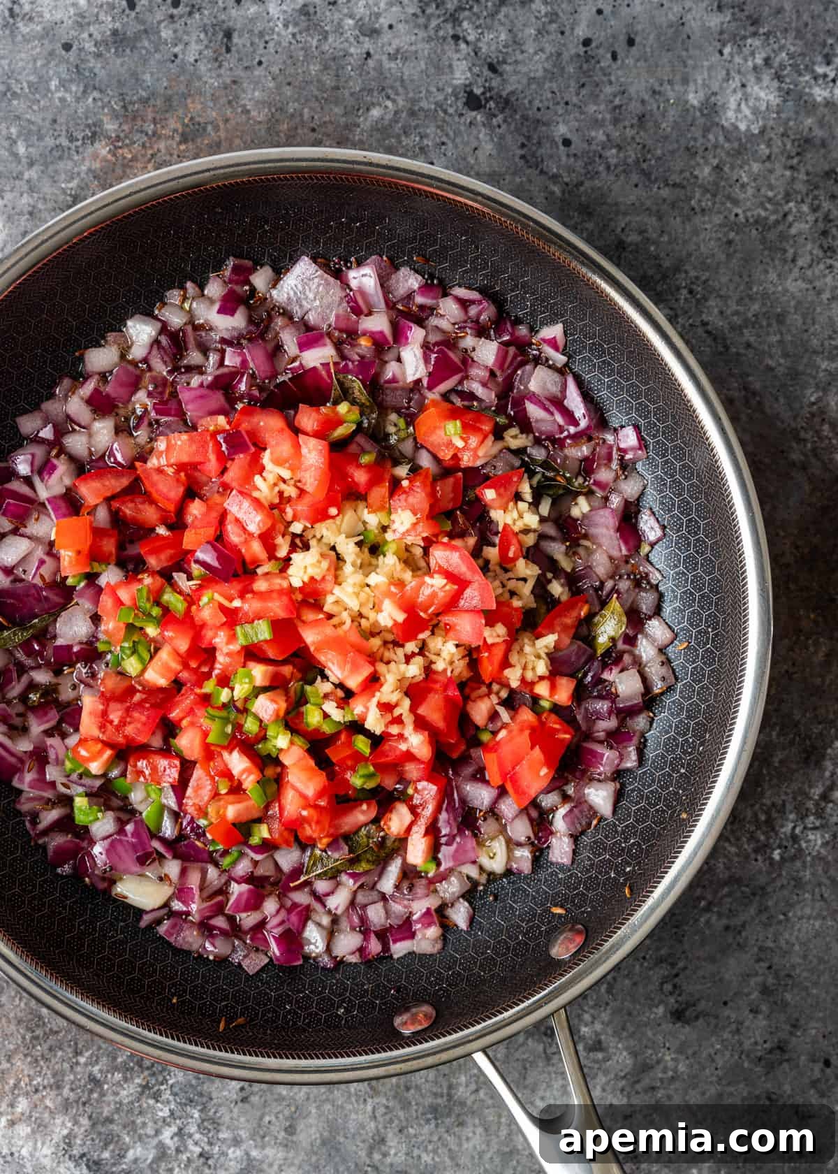 overhead process shot: adding tomatoes, chile, and ginger to the skillet