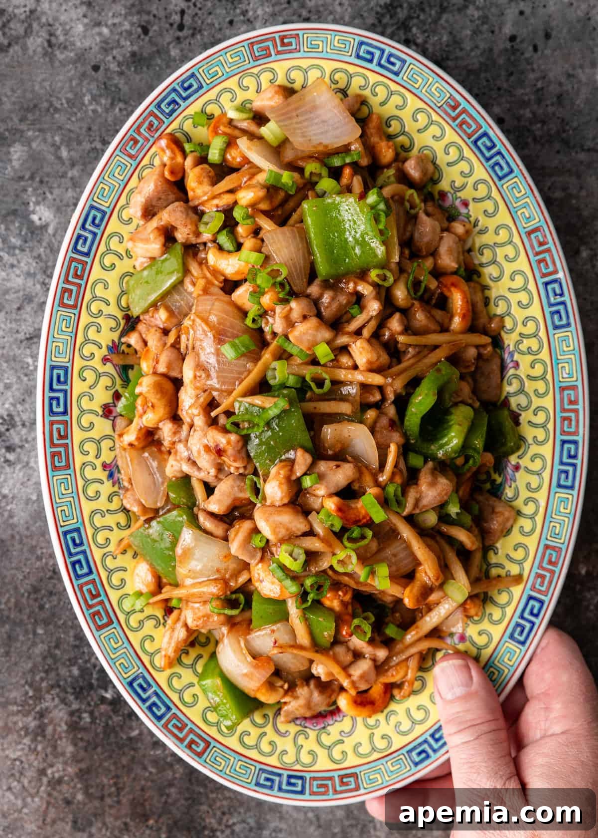 Delicious Cashew Chicken Stir-Fry 8 Overhead shot of a hand holding a serving platter of freshly cooked Cashew Chicken