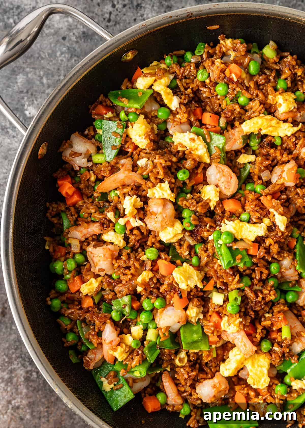 overhead: fried rice with shrimp, eggs, and vegetaables in a large skillet