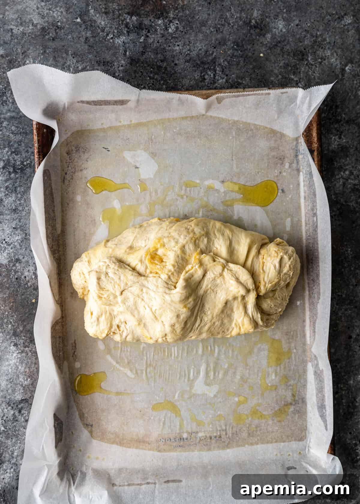 overhead process shot: dough folded into thirds on the oiled parchment