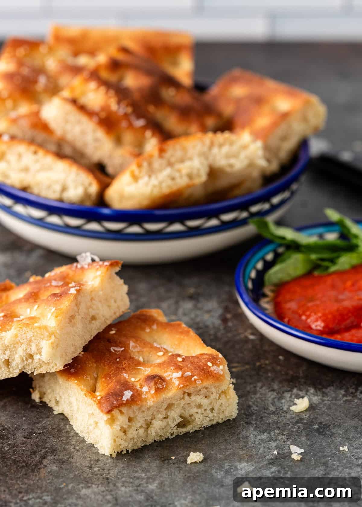 two slices of focaccia bread on a counter next to a bowl of marinara