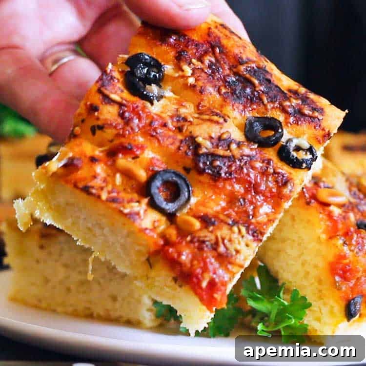 closeup: focaccia bread topped with marinara, olives, cheese, and pine nuts