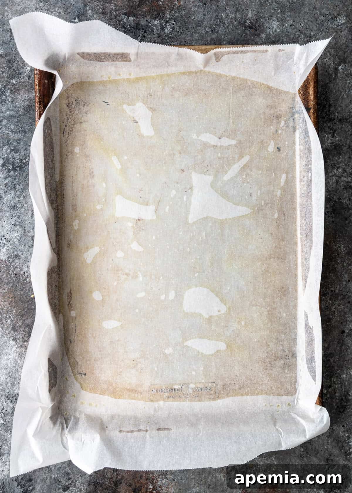 overhead process shot: oil added to baking sheet with parchment on top