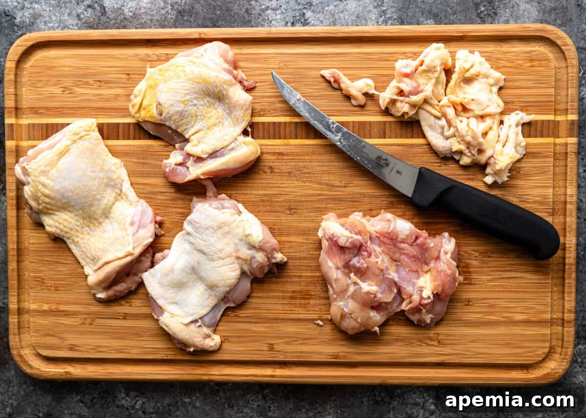 overhead process shot: trimming the chicken pieces with a knife on a wooden cutting board