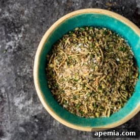 A charming image of a small, rustic wooden bowl generously filled with homemade Greek seasoning, ready to be used in cooking.