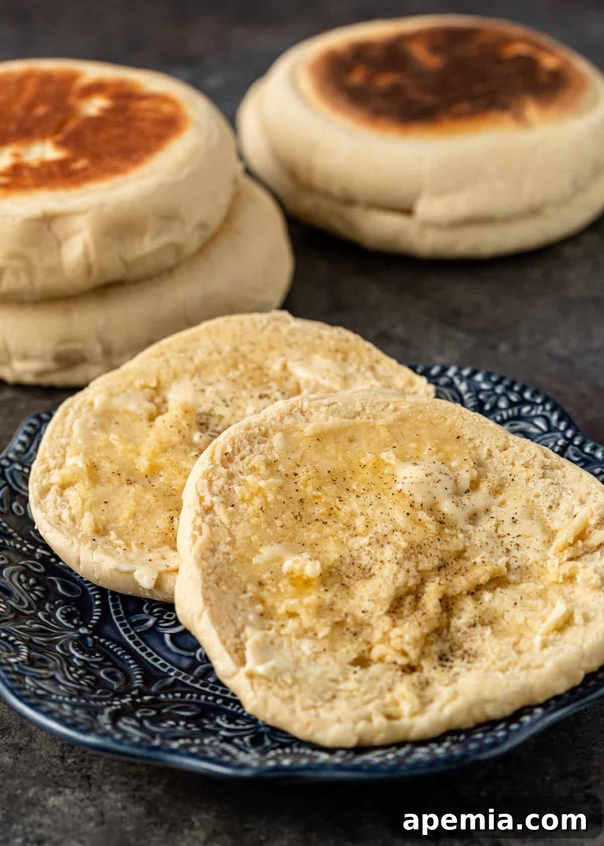 A bazlama flatbread sliced in half, generously topped with melted butter, a sprinkle of salt, and freshly ground pepper, ready to be served.