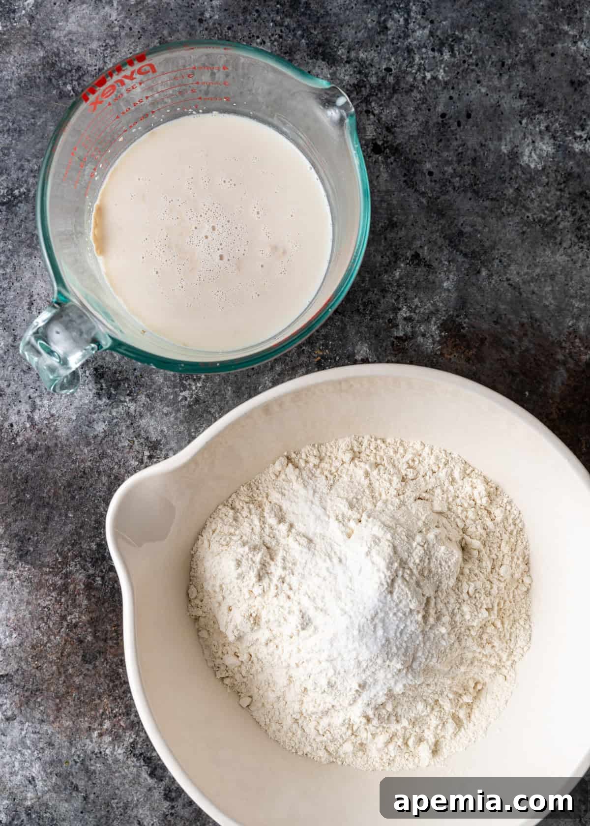 Overhead process shot: Wet ingredients (milk, water, sugar, yeast) in one bowl and dry ingredients (flour, salt) in another, ready to be combined for bazlama dough.