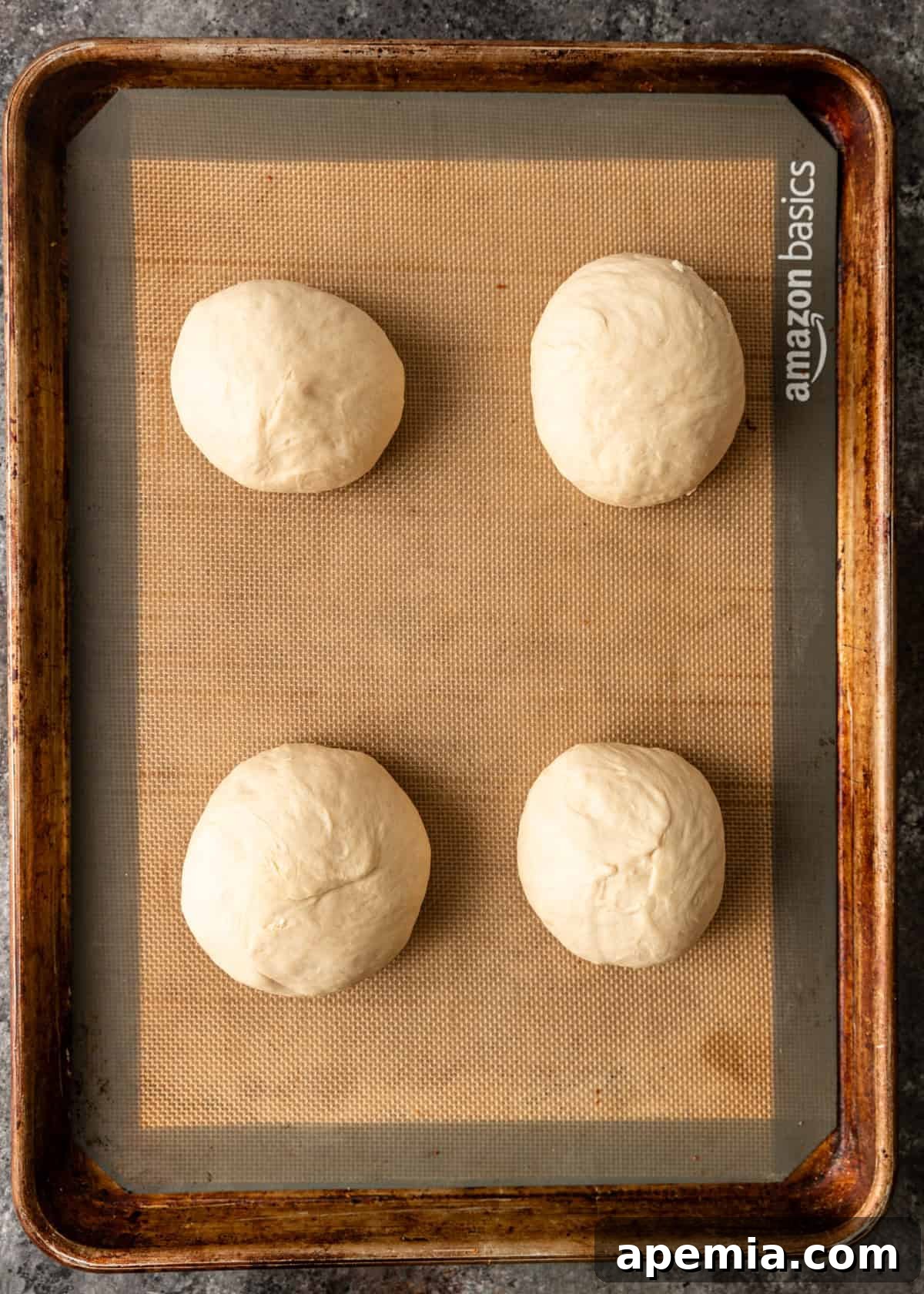 Overhead process shot: Four portions of bazlama dough expertly rolled into smooth, even balls, arranged neatly on a baking sheet, ready for flattening.