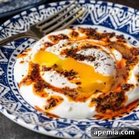 Turkish Çilbir (poached eggs with yogurt) in a bowl with chili butter and fresh mint.