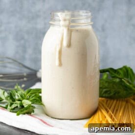 homemade alfredo sauce in glass jar with drip on side