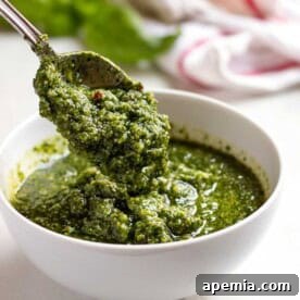 Spoonful of vibrant green basil pesto in a rustic white bowl, ready to be served