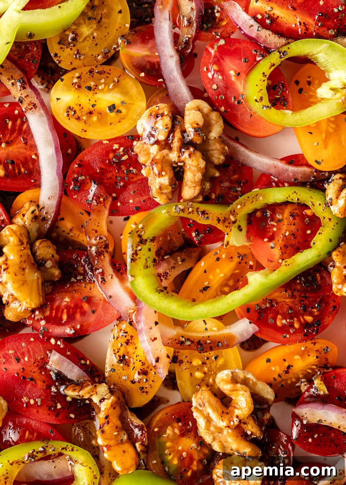 Extreme close-up of fresh Turkish tomato salad with chunky tomatoes, thinly sliced red onion, bright red pepper, and crunchy walnuts, showcasing the rich texture.