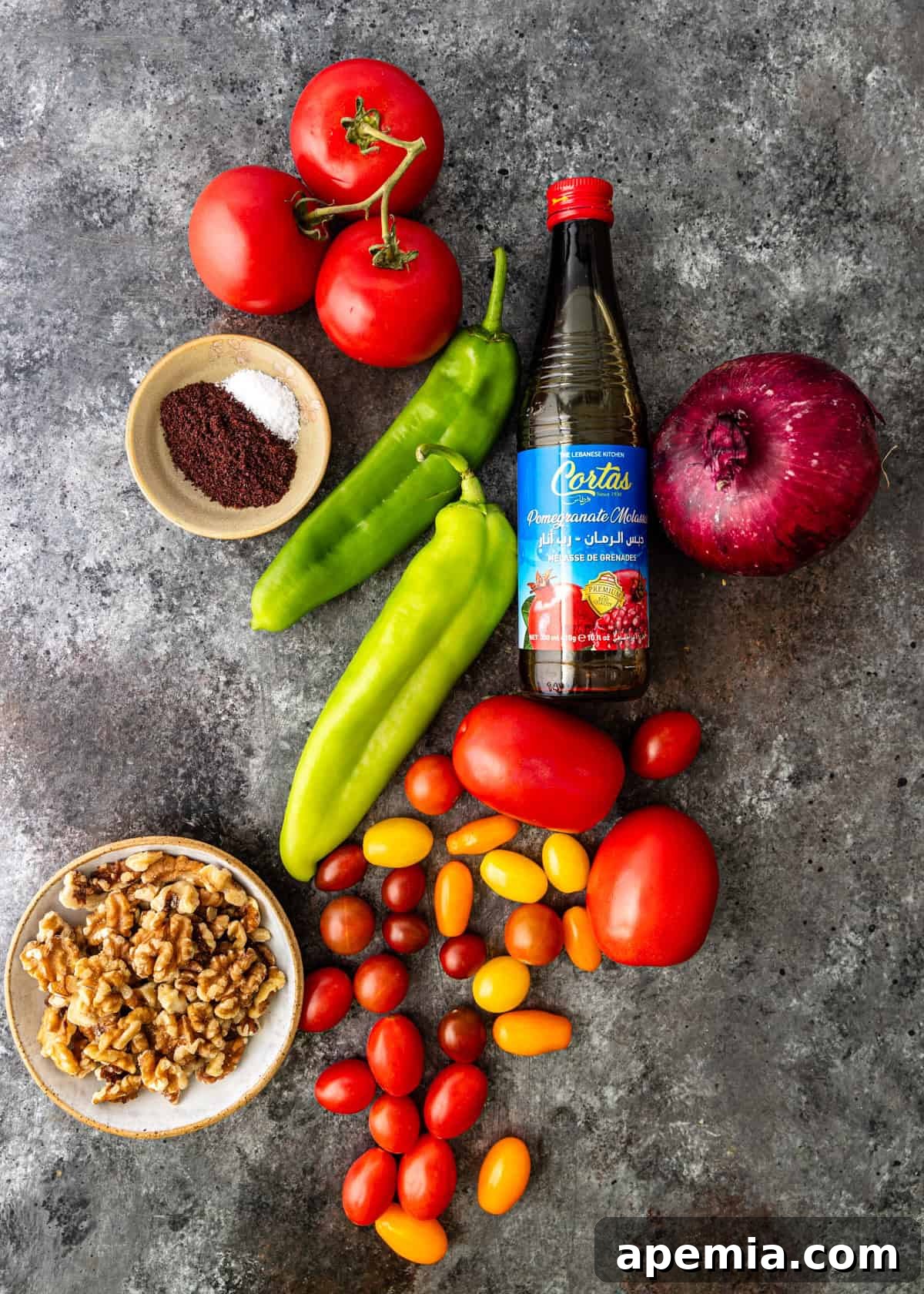 Ingredients laid out for Gavurdagi Salatasi: fresh tomatoes, green pepper, red onion, pomegranate molasses, olive oil, sumac, salt, pepper, and walnuts.