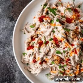 A small, mouth-watering image of the finished Turkish Circassian Chicken dish, garnished with fresh herbs and a drizzle of red pepper sauce.