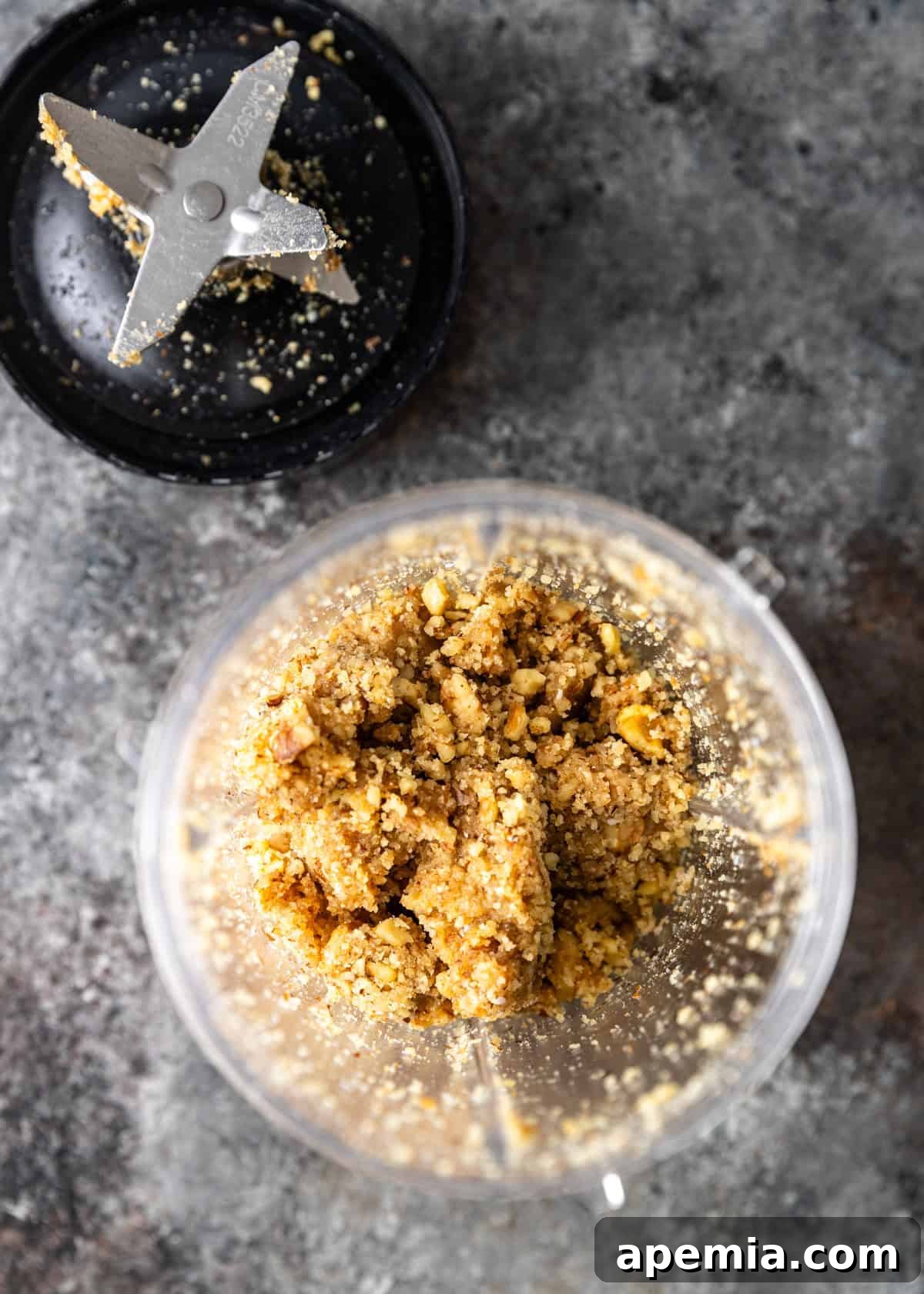 Overhead process shot: crumbled white bread, fresh garlic cloves, and walnuts waiting in a food processor, ready to be blended.