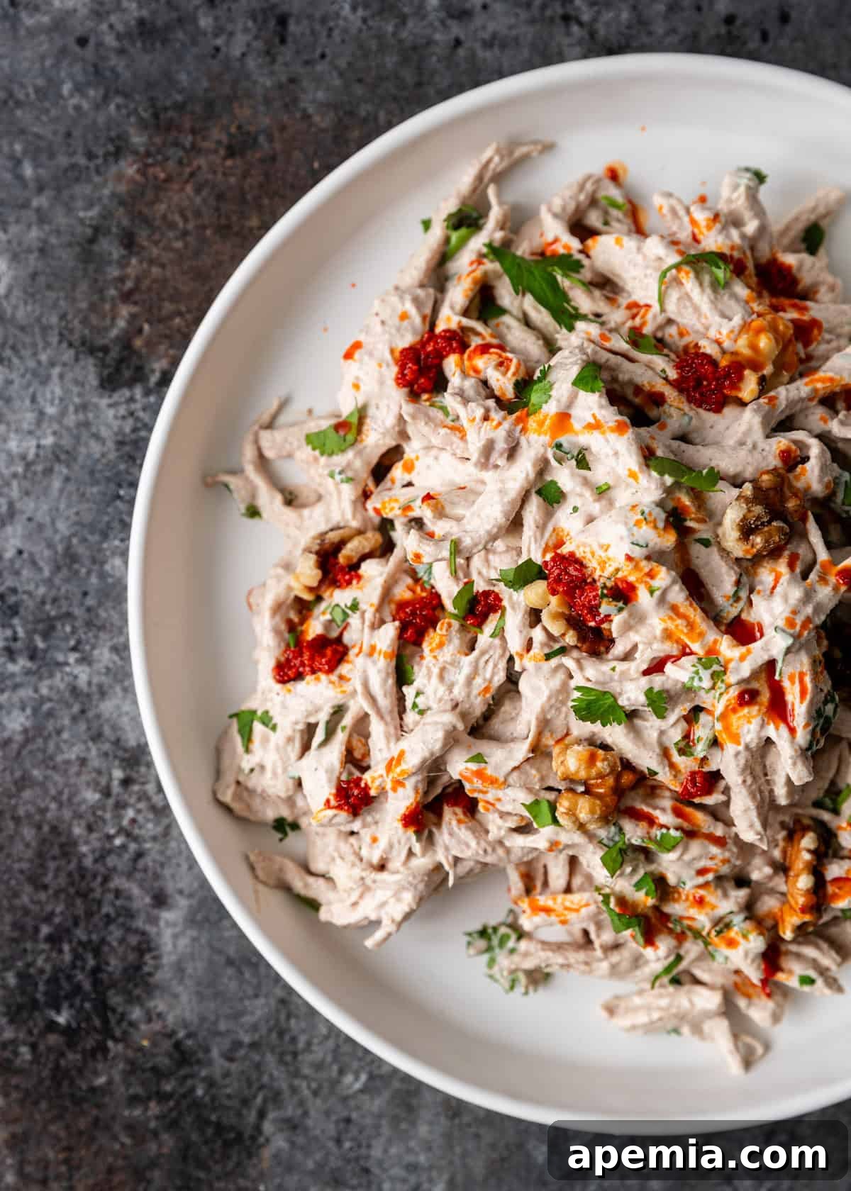 Overhead view of a large serving platter overflowing with Turkish chicken salad, adorned with fresh herbs and a generous swirl of creamy sauce on top, ready for guests.