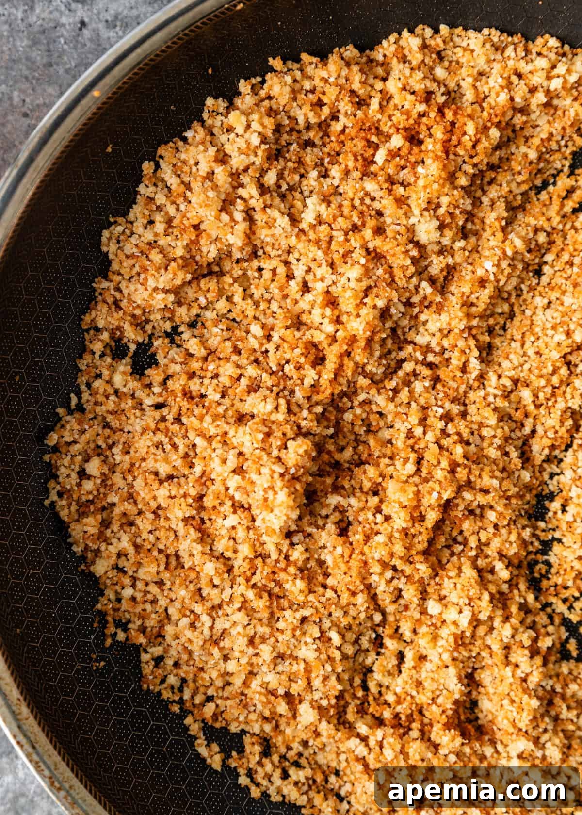 overhead closeup: breadcrumbs shimmering in olive oil in a skillet, turning golden for pangrattato