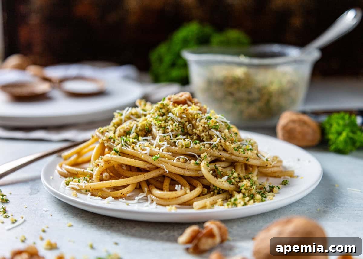 side view: a perfectly plated dish of brown butter bucatini generously topped with walnut pangrattato