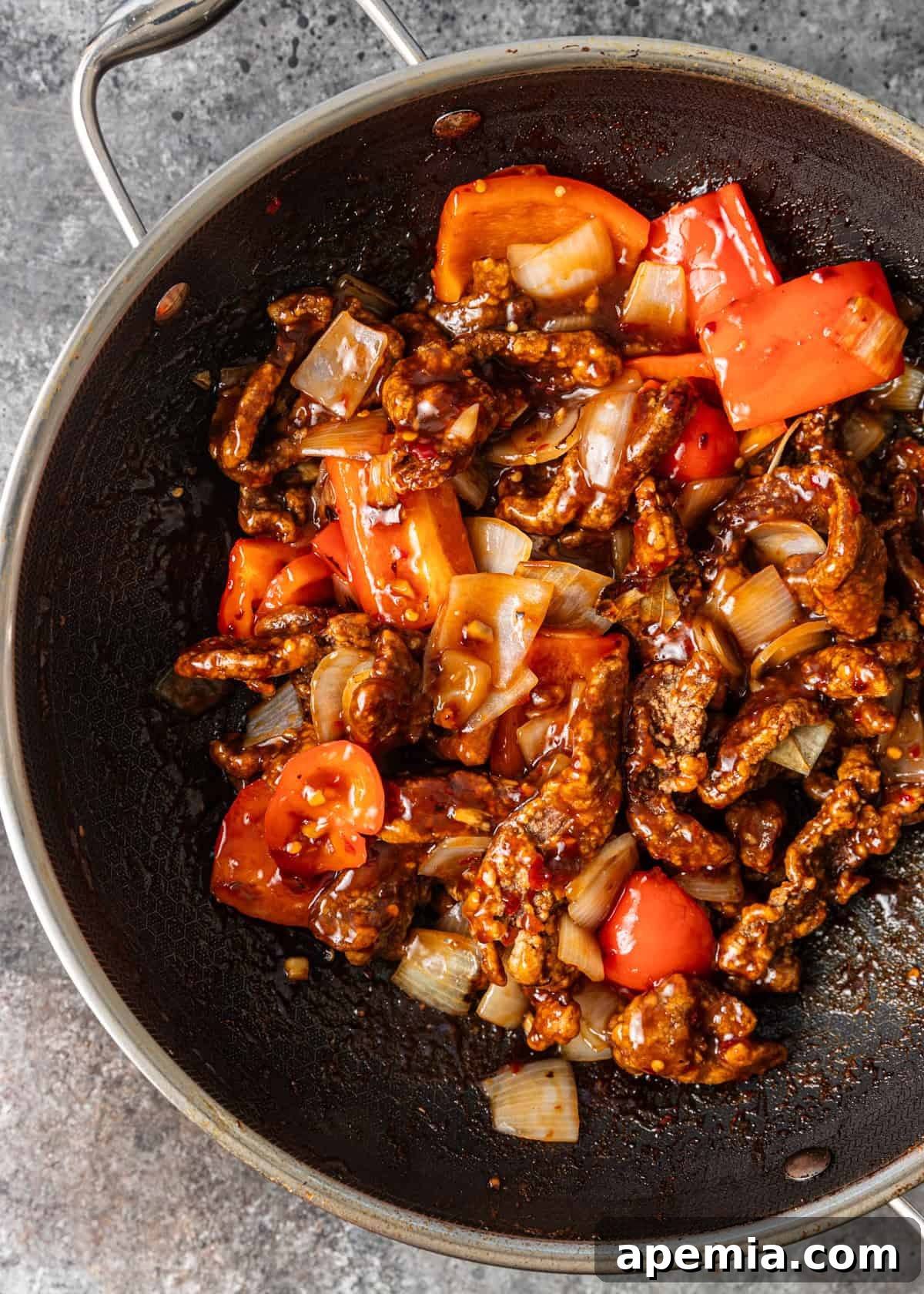 Sweet & Tangy Beijing Beef 6 Overhead view of Beijing Beef stir-frying in a large wok, with bell peppers and onions beautifully caramelized