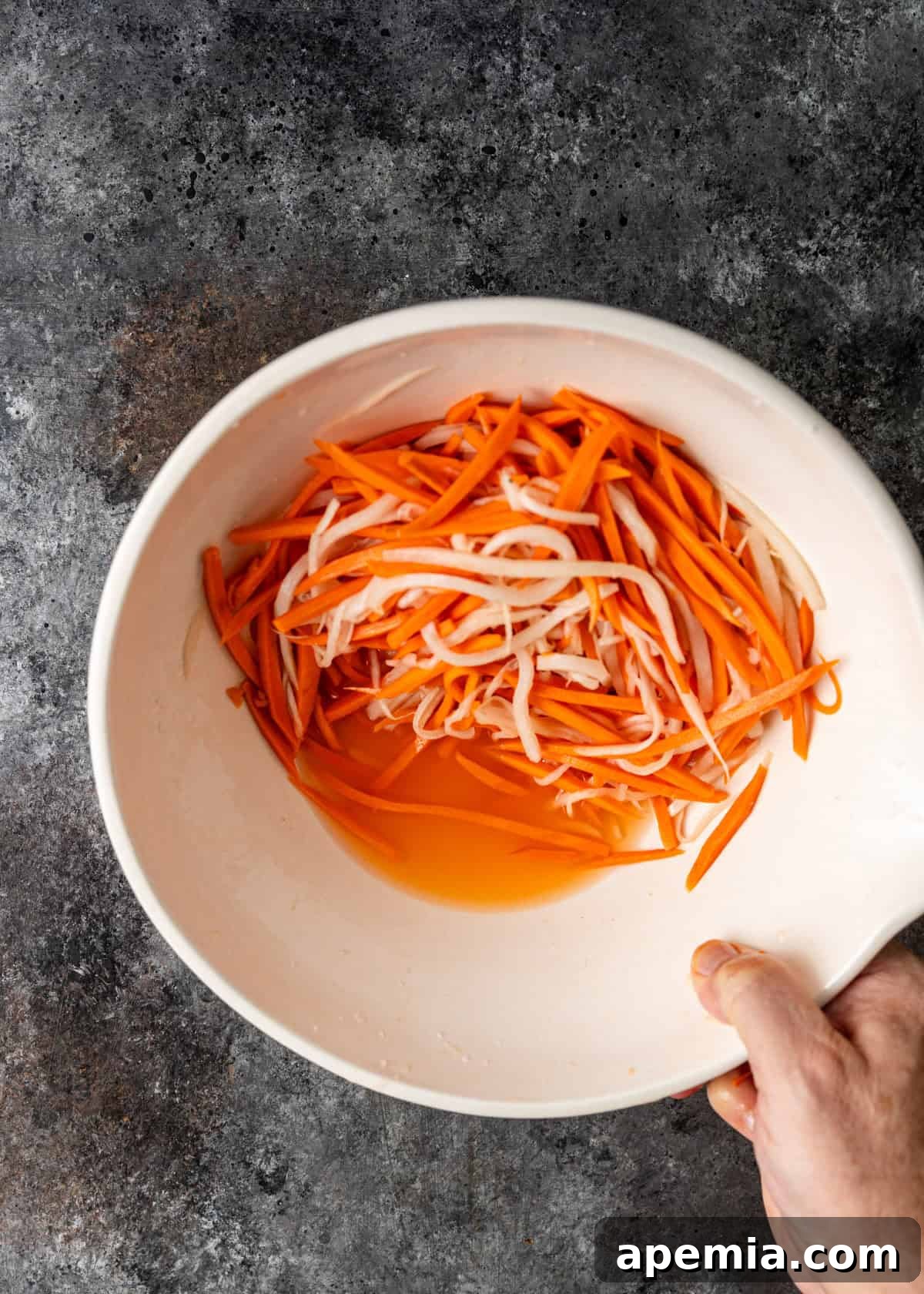 Crisp Vietnamese Pickled Daikon and Carrots 5 overhead process shot: limp salted carrots and daikon ready to drain
