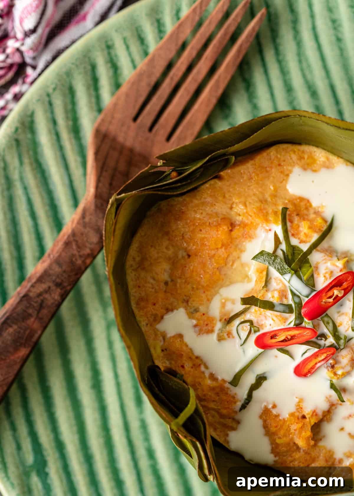overhead closeup: my amok recipe with coconut milk and chiles on top with a wooden fork to the side