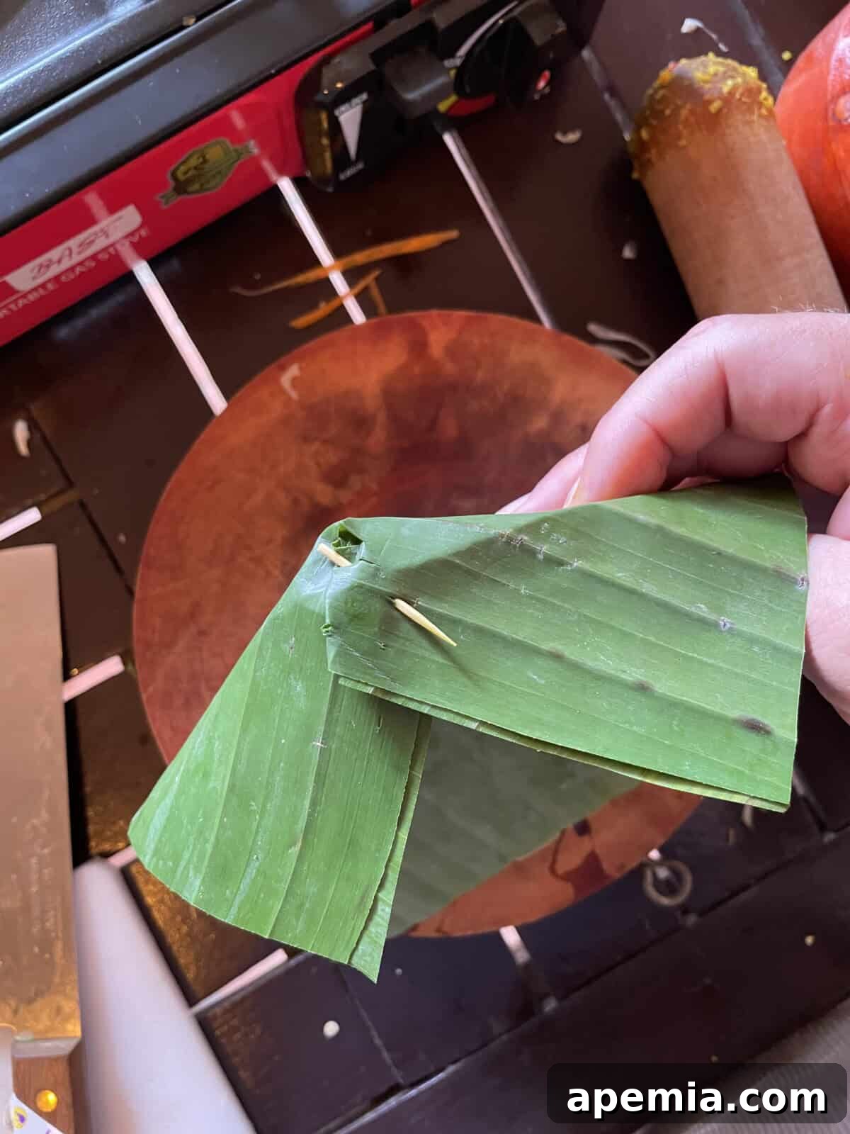 overhead process shot: making the pleat in a banana leaf and securing it with a toothpick